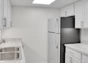 Thumbnail 7 of 36 - A kitchen with a sink, refrigerator, and cabinets.