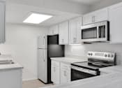 Thumbnail 6 of 36 - A kitchen with white cabinets and appliances.