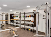 Thumbnail 6 of 30 - A gym with a variety of equipment including weights and a leg press machine.