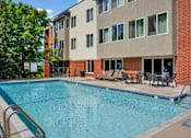 Thumbnail 9 of 30 - A swimming pool in front of a multi-story apartment building.
