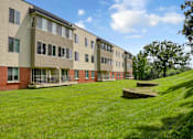 Thumbnail 20 of 30 - A long building with a green lawn in front.