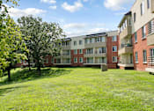 Thumbnail 24 of 30 - A grassy area in front of apartment buildings.