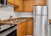 Thumbnail 27 of 30 - A kitchen with a stainless steel refrigerator and wooden cabinets.