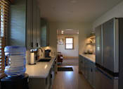 Thumbnail 21 of 27 - A kitchen with a white counter top and a water cooler.
