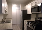 Thumbnail 15 of 27 - A kitchen with a black refrigerator, stove, and microwave.