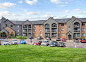 Thumbnail 55 of 67 - A row of apartment buildings with cars parked in front.