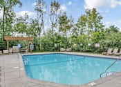 Thumbnail 52 of 67 - A large outdoor swimming pool surrounded by trees.
