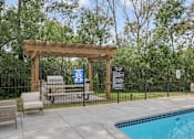 Thumbnail 46 of 67 - A pool area with a wooden pergola and a black fence.