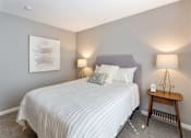 Thumbnail 30 of 41 - A bedroom with a bed, nightstand, and lamp.