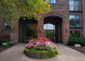 Thumbnail 2 of 49 - a large brick building with a flower garden in front of it