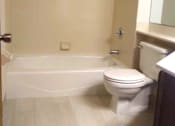 Thumbnail 44 of 49 - A white toilet sits in a bathroom next to a bathtub.
