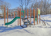 Thumbnail 24 of 27 - A playground with a green slide and orange structure in the snow.