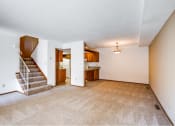 Thumbnail 25 of 36 - an empty living room with a staircase and a kitchen in the background