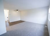 Thumbnail 7 of 18 - an empty living room with white walls and a ceiling fan