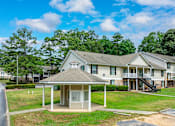 Thumbnail 6 of 19 - A house with a covered porch and a tree in the background.