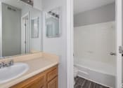 Thumbnail 18 of 19 - A white bathroom with a sink, mirror, and bathtub.