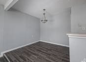 Thumbnail 16 of 19 - A room with a wooden floor and a chandelier hanging from the ceiling.