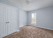 Thumbnail 11 of 19 - A room with a carpeted floor, a window, and a white door.