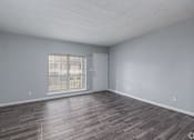 Thumbnail 15 of 19 - A room with a wooden floor and a sliding glass door.