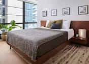 Thumbnail 13 of 15 - A bedroom with a large bed and a view of a city skyline.