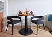 Thumbnail 12 of 15 - A round table with two chairs and a bowl of fruit on it.
