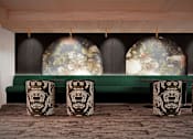 Thumbnail 7 of 15 - A room with a green sofa and a table with a floral design.