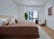 Thumbnail 7 of 15 - A bedroom with a large bed and a chair.