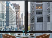 Thumbnail 5 of 15 - Two tan chairs are placed in front of a table with a view of the city.