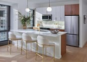 Thumbnail 4 of 15 - A modern kitchen with white and gold chairs.