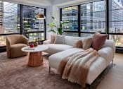Thumbnail 1 of 15 - A living room with a white couch and a brown chair.