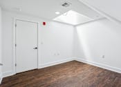 Thumbnail 30 of 36 - A room with a white door and wooden flooring.