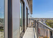 Thumbnail 20 of 32 - A balcony with a metal railing and glass doors overlooking a cityscape.