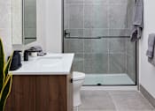 Thumbnail 6 of 15 - A modern bathroom with a walk-in shower and a white sink.