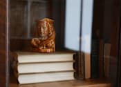Thumbnail 6 of 32 - A wooden sculpture of a man's face is sitting on top of a stack of books.