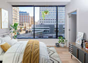 Thumbnail 15 of 42 - A bedroom with a large bed and a view of the city.