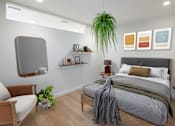 Thumbnail 13 of 42 - A bedroom with a bed, chair, and potted plant.