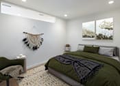 Thumbnail 19 of 42 - A bedroom with a green bed and a wall hanging.