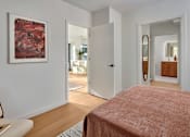 Thumbnail 6 of 15 - A bedroom with a red bedspread and a painting on the wall.