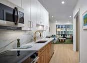 Thumbnail 9 of 15 - A modern kitchen with a marble countertop and stainless steel appliances.