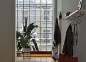 Thumbnail 7 of 13 - a living room with a large window and a bench with a bag and a plant