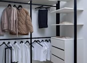Thumbnail 8 of 15 - A white closet with clothes and a suitcase.