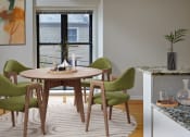 Thumbnail 4 of 13 - a dining room with a round wooden table and green chairs