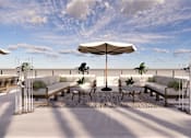 Thumbnail 12 of 15 - A white patio with a large umbrella and chairs.