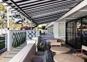 Thumbnail 7 of 30 - A patio with a black and white striped awning and a table with chairs at The PARKER on E Mulberry Apartments, San Antonio