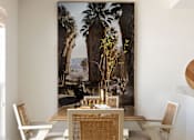 Thumbnail 21 of 30 - A dining room with a table set for two and a large painting of a palm tree in the background at The PARKER on E Mulberry Apartments, Texas