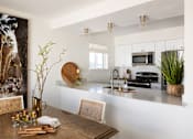 Thumbnail 20 of 30 - A modern kitchen with a wooden table and chairs at The PARKER on E Mulberry Apartments, Texas