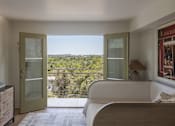 Thumbnail 26 of 30 - A bedroom with a bed, dresser, and a balcony with a view of the trees at The PARKER on E Mulberry Apartments, San Antonio
