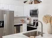 Thumbnail 27 of 30 - A modern kitchen with a stainless steel refrigerator and a white countertop at The PARKER on E Mulberry Apartments, San Antonio, Texas