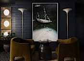 Thumbnail 14 of 30 - A room with a large picture of a boat on the wall and two yellow chairs at The PARKER on E Mulberry Apartments, San Antonio, Texas