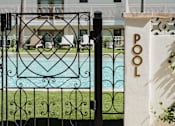 Thumbnail 9 of 30 - A pool with a black fence and a white pillar with the word POOL on it at The PARKER on E Mulberry Apartments, San Antonio, TX